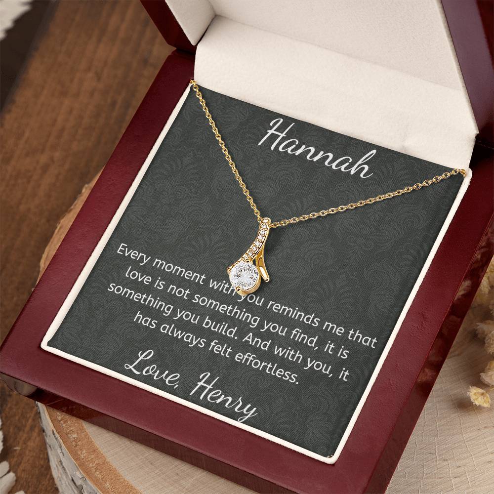 Gold necklace on a card with a sentimental message, placed on a wooden surface.