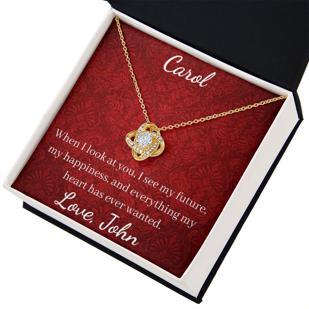 Gold necklace with heart pendant on a red card with personalized text, displayed in an open jewelry box.