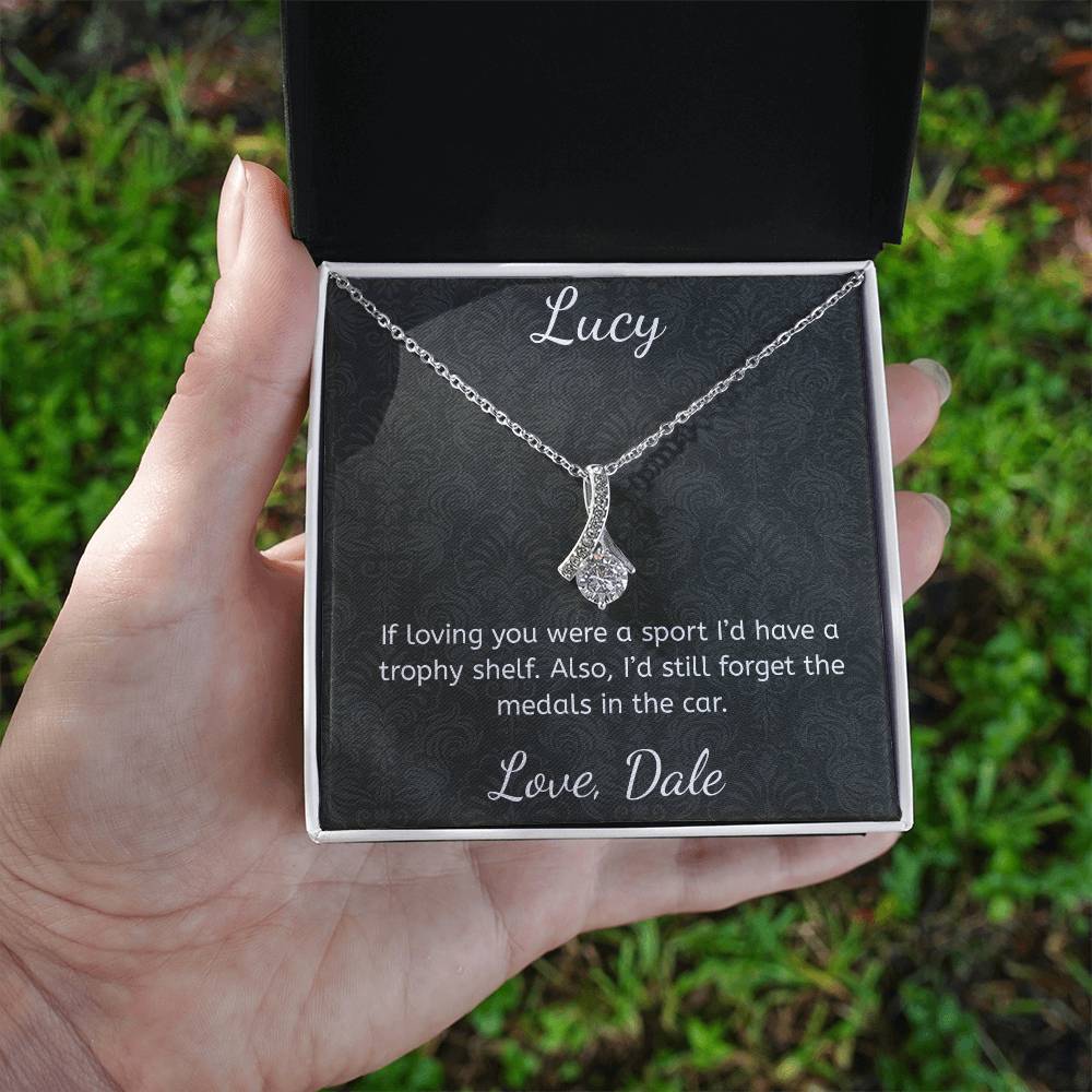 Necklace in a box with personalized message held by a hand against a grassy background