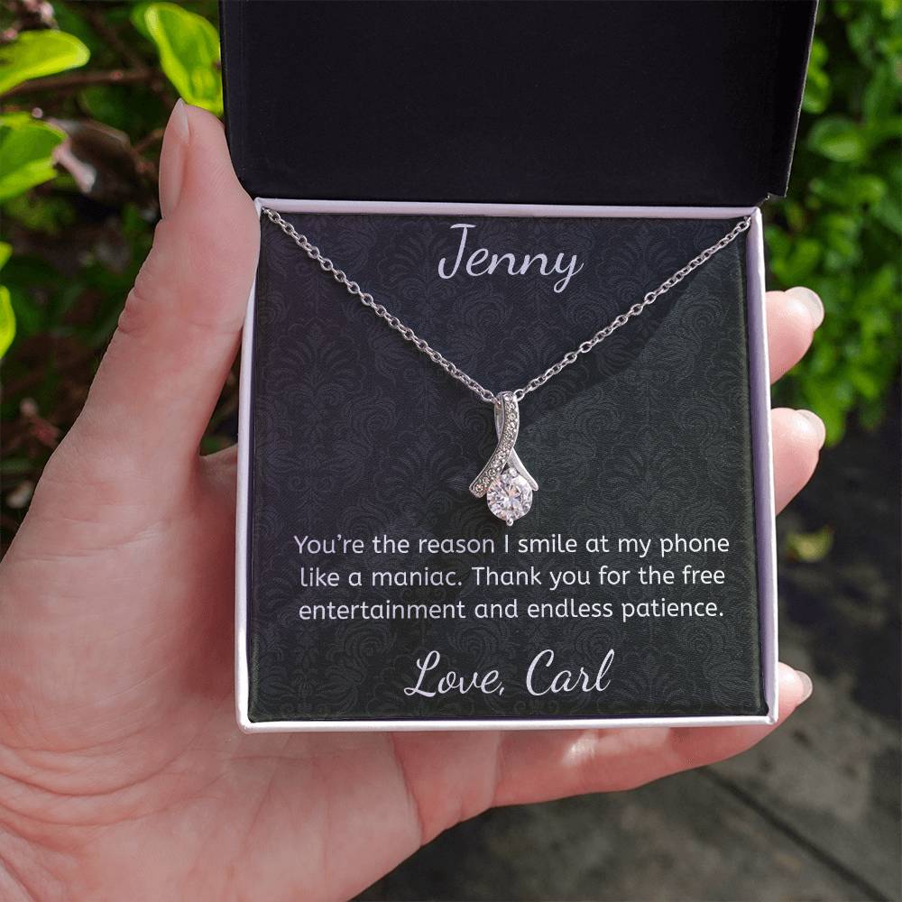 Silver necklace in a personalized gift box held by a hand with greenery in the background